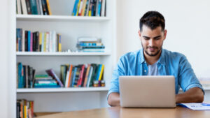 Mexican hipster man working with computer indoor at desk at home