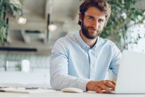 Businessman in shirt working on his laptop in an office. Open space office