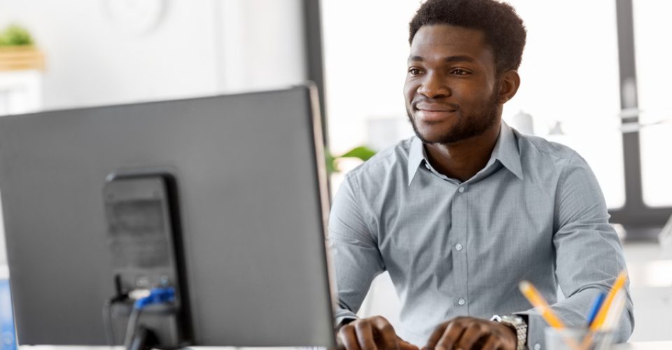 business, people and technology concept - african american businessman with computer working at office